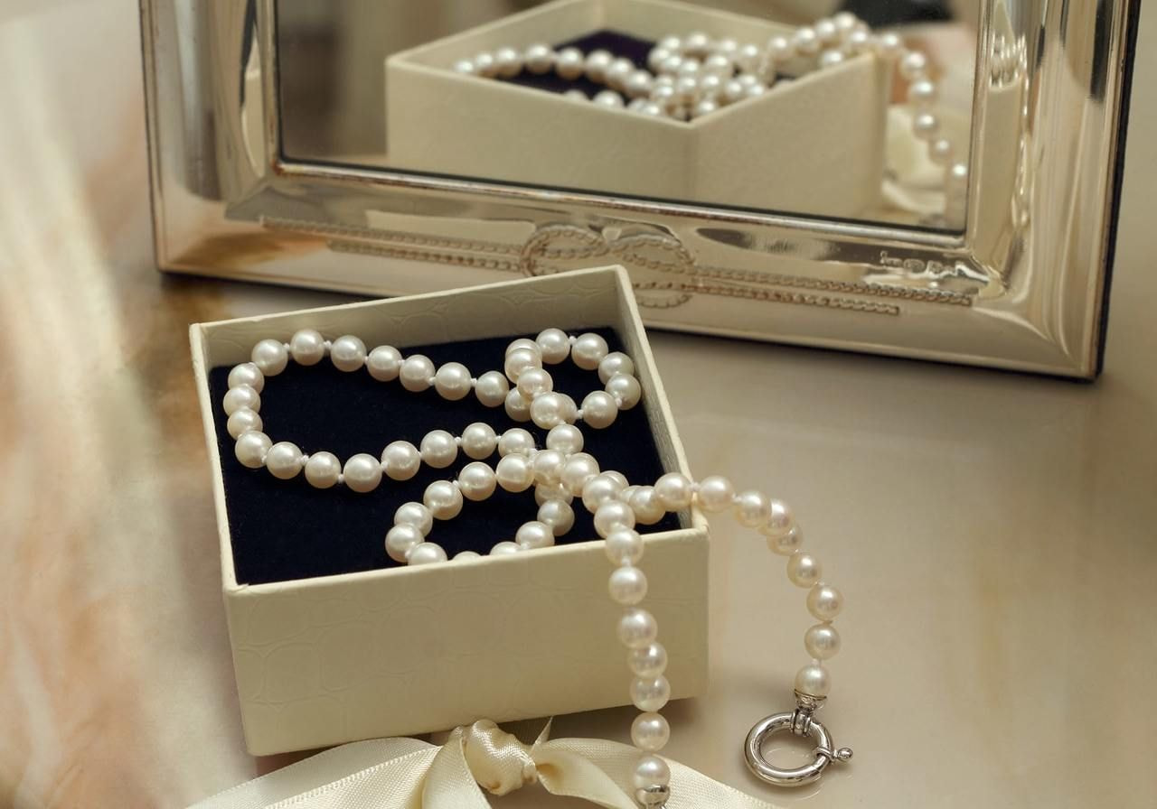 A jewelry box on a table containing a necklace and a pearl necklace.